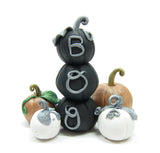 Stack of black pumpkins with miniature polymer clay figurines