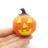 Miniature polymer clay pumpkin with yellow face cutouts