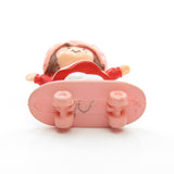 Strawberry Shortcake riding on a skateboard miniature figurine