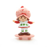 Strawberry Shortcake riding on a skateboard miniature figurine