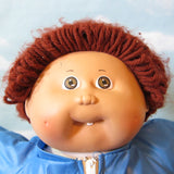 Boy Cabbage Patch Kids doll with brown hair, brown eyes, tooth, dimples